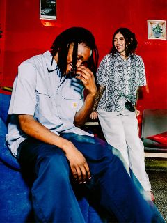 Zwei junge Erwachsene lachen zusammen in einem hell erleuchteten Raum mit roten Wänden und moderner Einrichtung.