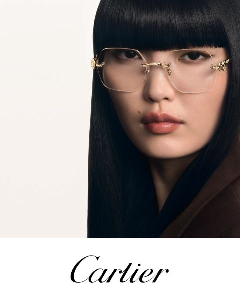 Frau mit glattem schwarzem Haar und goldgerahmter Brille blickt in die Kamera. Darunter steht in eleganter Schrift "Cartier".