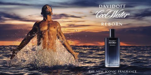 Ein Mann ohne Hemd taucht mit ausgebreiteten Armen aus dem Meer auf. Der Himmel ist in Orange- und Lilatönen gehalten, was auf einen Sonnenuntergang oder Sonnenaufgang hindeutet. Im Vordergrund ist eine Flasche Davidoff Cool Water Reborn-Parfüm zu sehen. Der Text lautet „Der neue Kultduft“.