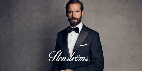 Ein Mann mit Bart trägt einen schwarzen Smoking und eine Fliege vor einem schlichten Hintergrund. Er blickt geradeaus, und das Wort „Stenströms“ ist in kursiver Schrift deutlich über das Bild zu lesen.