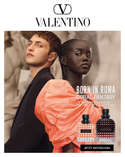 Zwei Models stehen Rücken an Rücken, die Frau trägt ein orangefarbenes Outfit. Im Vordergrund sind zwei Parfümflakons zu sehen. Der Text lautet: „Valentino: Born in Roma Coral Fantasy. Die neuen Düfte für sie, ihn oder sie. Jetzt entdecken.“.