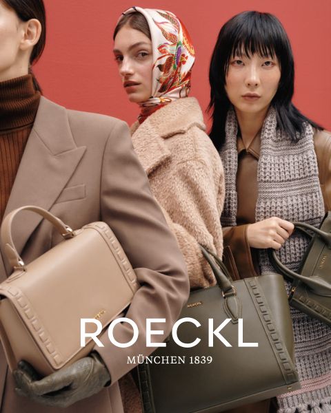 Drei Models stehen vor einem roten Hintergrund und halten jeweils eine Designer-Handtasche von Roeckl in der Hand. Das linke Model trägt einen braunen Rollkragenpullover und Mantel, das mittlere ein buntes Kopftuch und das rechte Model einen grauen Schal und einen dunklen Mantel. Der Text lautet „ROECKL MÜNCHEN 1839.