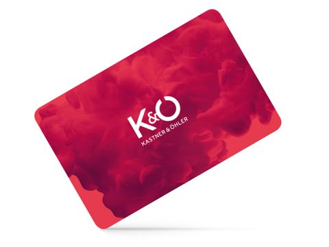 Eine rote Geschenkkarte mit den weißen Buchstaben „K&O“ und darunter der Schriftzug „KASTNER & ÖHLER“. Der Hintergrund ist mit einem wirbelnden roten Rauchmuster versehen.