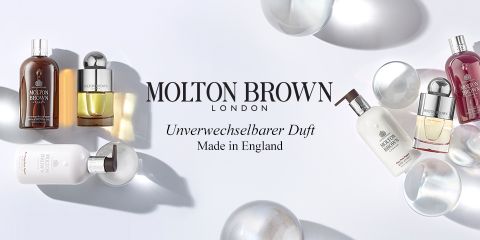 Flache Anordnung verschiedener Molton Brown-Flaschen und -Behälter auf hellem Hintergrund, mit dem Text „Molton Brown London, Unverwechselbarer Duft, Made in England“ in der Mitte. Überall sind kugelförmige Glasakzente verstreut.