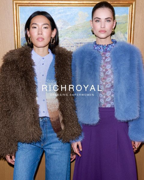 Zwei Frauen stehen Seite an Seite vor einem gerahmten Gemälde und tragen elegante Pelzjacken und gewagte Mode. Der Text "RICHROYAL Dressing Superwomen" ist in der Mitte des Bildes überlagert.