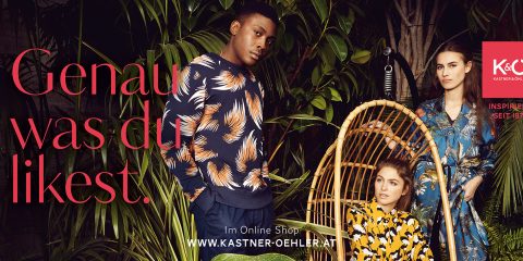 Drei Models in stylischen, gemusterten Outfits stehen und sitzen inmitten üppiger grüner Pflanzen. Der Text lautet „Genau was du likest“. Oben rechts befindet sich ein rotes Logo mit „Kastner & Öhler“. Unten in der Mitte steht die Website-URL.