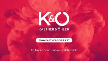 Roter Hintergrund mit weißem Text, auf dem „K&O Kastner & Öhler“ und ihre Website „www.kastner-oehler.at“ stehen. Der Text erwähnt ihren Online-Shop und 14 Standorte in Österreich. Das Design enthält ein wolkenähnliches abstraktes Muster.