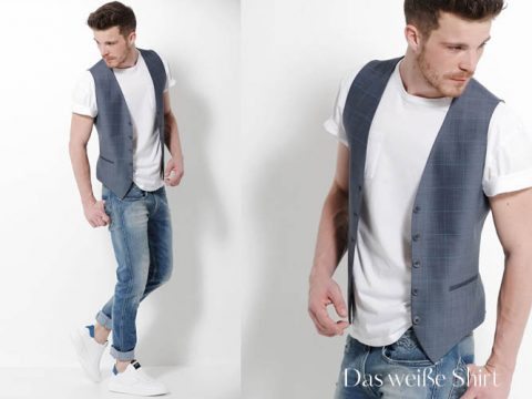 Ein Mann mit kurzen braunen Haaren trägt ein weißes T-Shirt, eine grau karierte Weste und blaue Jeans. Er posiert stehend und an einer weißen Wand lehnend. Er trägt weiße Turnschuhe und darunter steht der Text „Das weiße Shirt“.