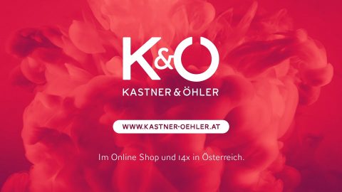 Roter Hintergrund mit wirbelnden Mustern und einem weißen Logo mit der Aufschrift „Kastner & Öhler“. Unter dem Logo befindet sich ein Website-Link www.kastner-oehler.at, gefolgt von einem Text, der auf Online-Shopping und 14 Standorte in Österreich hinweist.