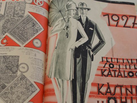 Vintage-Katalog aus dem Jahr 1927 mit illustrierten Models in stilvoller Kleidung. Die Frau hält einen Regenschirm und der Mann trägt einen Anzug. Der Hintergrund enthält gemusterte Designs und Text in deutscher Sprache zu Modeprodukten.