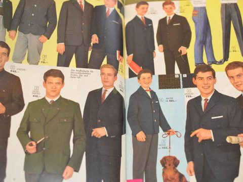 Eine Vintage-Katalogseite mit Herrenanzügen und -jacken. Die Models tragen formelle Kleidung und halten Accessoires wie Pfeifen und Handschuhe in der Hand. Stoffmuster und Preise werden neben den Models in einem Layout im Retro-Stil angezeigt.