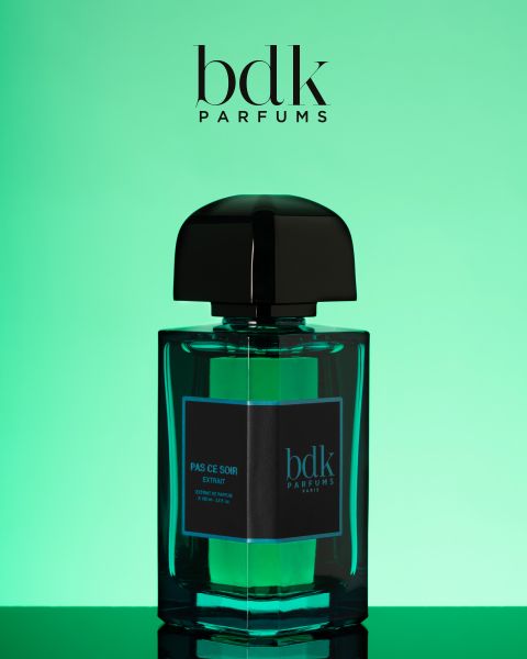 Eine Flasche BDK Parfums „Pas Ce Soir“-Extrait mit einem eleganten schwarzen Verschluss wird vor einem grünen Hintergrund mit Farbverlauf präsentiert. Das Logo von BDK Parfums ist oben im Bild zu sehen.
