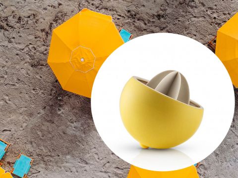 Eine gelbe Zitruspresse in einer kreisförmigen Einlage überlagert ein Bild von gelben Sonnenschirmen und leeren türkisfarbenen Liegestühlen an einem Sandstrand.