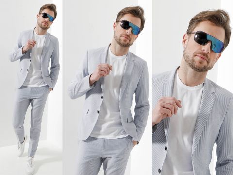 Ein Mann posiert selbstbewusst in einem hellgrauen Anzug und einem weißen T-Shirt und trägt eine große verspiegelte Sonnenbrille. Das Bild ist eine Collage aus drei Winkeln: Gehen, Brille zurechtrücken und eine Nahaufnahme des Gesichts.