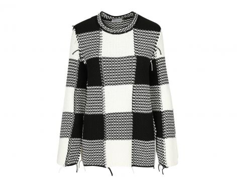 Ein schwarz-weiß karierter Pullover mit Rundhalsausschnitt und langen Ärmeln. Das Muster besteht aus großen Quadraten und der Stoff scheint strukturiert gestrickt zu sein.