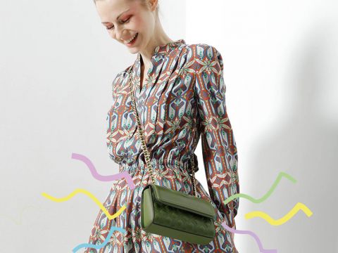 Eine Person in einem gemusterten Kleid lächelt und schaut nach unten. Sie trägt eine grüne Umhängetasche. Bunte Schnörkel rahmen den unteren Teil des Bildes vor einem hellen Hintergrund ein.
