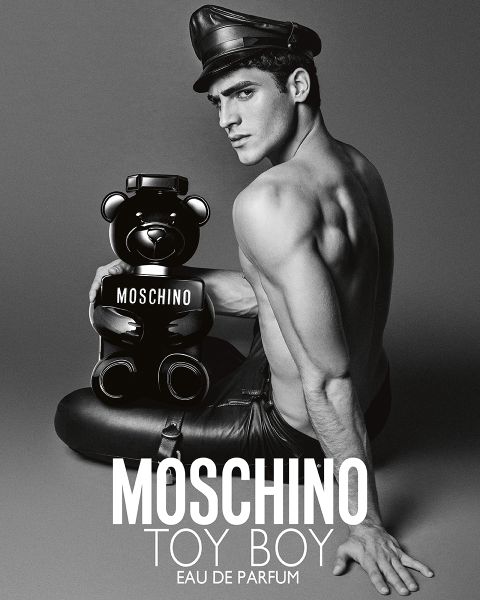 Hemdloser Mann in Lederhose und Hut hält einen Flakon mit Moschino-Parfüm in Form eines Teddybären. Text: "MOSCHINO TOY BOY EAU DE PARFUM.