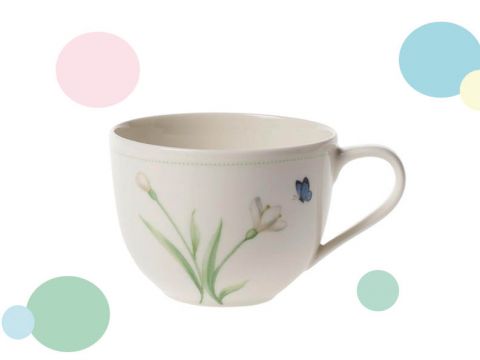 Eine weiße Teetasse mit Henkel zeigt zarte grüne Blatt- und Blumenmuster sowie einen kleinen blauen Schmetterling. Der Hintergrund ist weiß mit verstreuten pastellfarbenen Kreisen in Rosa, Blau, Grün und Gelb.