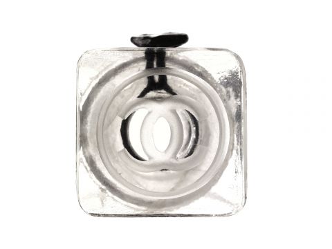 Nahaufnahme einer transparenten, quadratischen Glasflasche von oben. Auf der Unterseite ist ein verschlungenes kreisförmiges Muster zu sehen. Der Flaschenverschluss ist oben im Bild zu sehen.