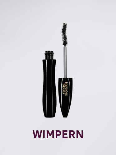 Eine Tube Lancôme Hypnôse Drama Mascara mit aufrecht stehender Bürste. Die Mascara ist schwarz und die Verpackung ist elegant mit dezenten goldenen Akzenten. Darunter steht in fetten violetten Buchstaben das Wort „WIMPERN“.