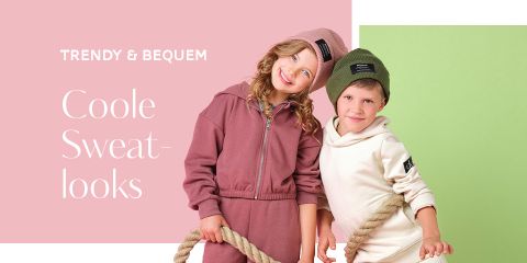 Zwei Kinder lächeln und tragen kuschelige Sweat-Outfits. Das Mädchen trägt einen rosafarbenen Hoodie und eine Mütze, der Junge einen cremefarbenen Hoodie und eine grüne Mütze. Sie halten ein dickes Seil. Der Text lautet „Trendy & Bequem Coole Sweatlooks“ auf pastellfarbenem Hintergrund.