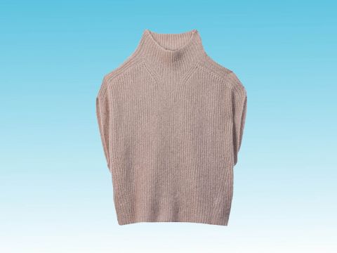 Ein beigefarbener Strickpullover mit hohem Kragen steht zentriert vor einem Hintergrund mit Farbverlauf in Blau. Der Pullover hat ein einfaches, gemütliches Design.