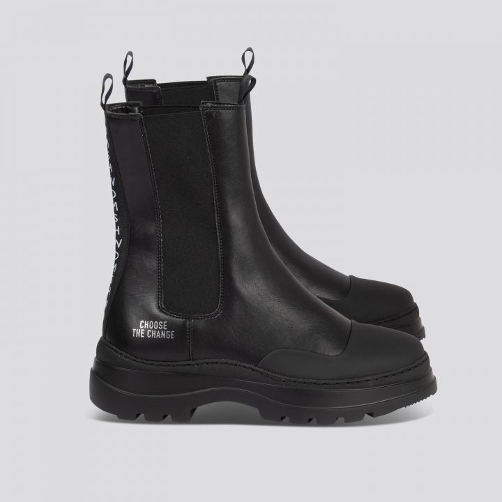 Schwarze Stiefeletten in Knöchelhöhe mit dicker Sohle und elastischen Seitenteilen. Auf der Seite ist der Text „Choose the Change“ aufgedruckt. Die Stiefel sind auf einem schlichten hellen Hintergrund platziert.