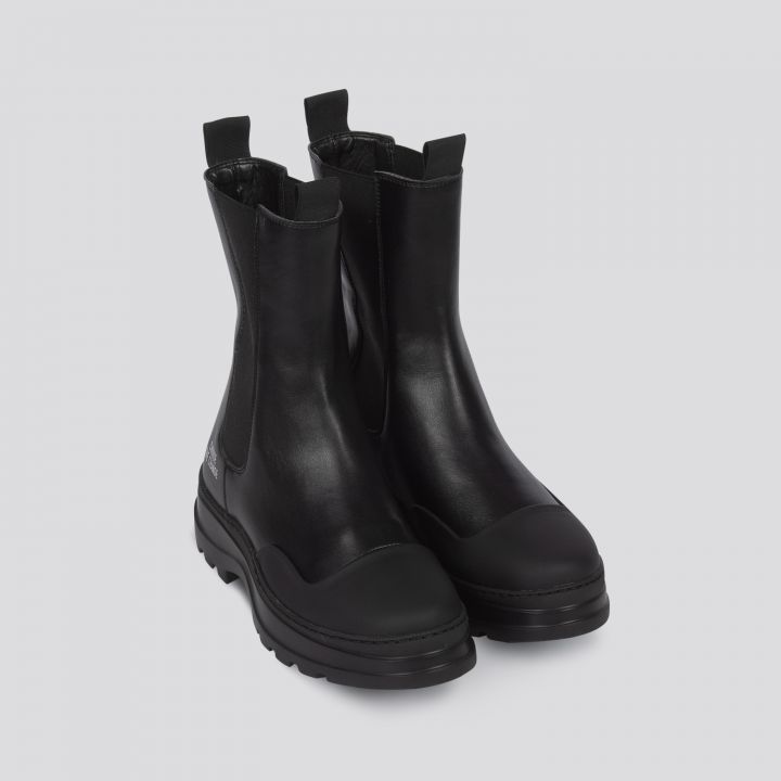 Ein Paar schwarze Lederstiefeletten mit dicker Sohle und elastischen Seiteneinsätzen. Sie haben ein elegantes Design mit Laschen an der Rückseite, die auf einem schlichten grauen Hintergrund abgebildet sind.