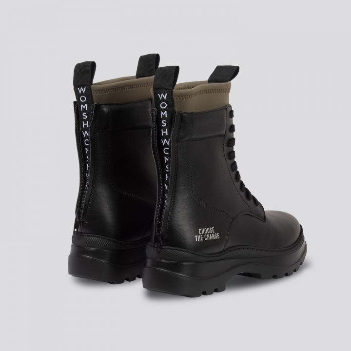 Ein Paar schwarze Lederstiefel mit dem Text „CHOOSE THE CHANGE“ auf der Ferse. Die Rückseite ist mit Laschen mit weißen und blauen Buchstaben versehen. Die Sohlen sind dick und robust und auf Langlebigkeit und Stil ausgelegt.