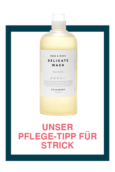 Eine Flasche Feinwaschmittel mit der Aufschrift „Rose & Musk“ von Steamery. Sie steht auf einem weißen Hintergrund mit Rand und rotem Text darunter: „Unser Pflege-Tipp für Strick“.