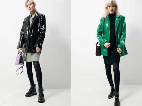 Zwei Models tragen glänzende, übergroße Jacken: eines in Schwarz mit einer lavendelfarbenen Handtasche und einem grünen Rock; das andere in Grün über einem schwarzen Outfit mit einer schwarzen Handtasche. Beide tragen schwarze Stiefel und Strumpfhosen und posieren vor einem schlichten weißen Hintergrund.
