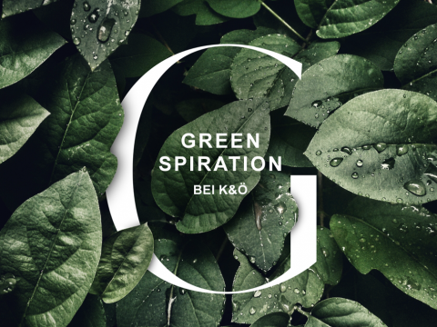 Eine Nahaufnahme von grünen Blättern mit Wassertropfen. In der Mitte steht in weißer Schrift das Wort „GREENSPIRATION“, darunter „BEI K&O“. Der große weiße Buchstabe „G“ umrahmt den Text.