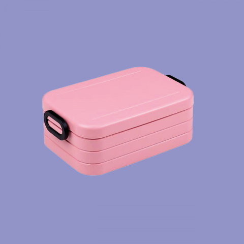 Eine rosa Bento-Box mit rechteckiger Form und schwarzen Griffen auf hellviolettem Hintergrund. Die Box hat mehrere Schichten, ideal für die Aufbewahrung und den Transport von Mahlzeiten.