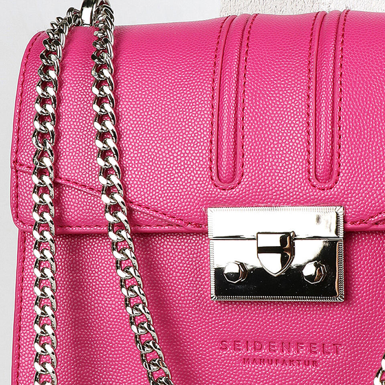 Nahaufnahme einer rosa Lederhandtasche mit glänzendem silbernem Kettenriemen und Metallverschluss. Die Textur der Tasche ist detailliert und der Markenname ist auf der Vorderseite eingeprägt.