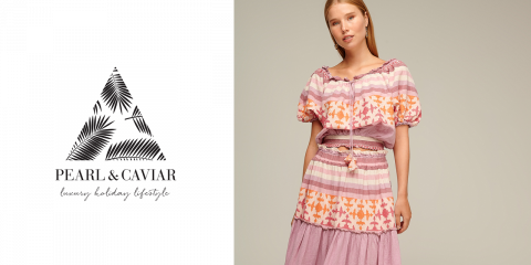 Eine Frau trägt ein rosa und orange gemustertes Kleid und steht vor einem neutralen Hintergrund. Links von ihr ist ein Logo mit einem Dreieck mit Blattmuster und dem Text „PEARL & CAVIAR Luxus-Urlaubs-Lifestyle“ zu sehen.