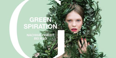 Eine Frau umgeben von üppigem grünem Laub auf hellgrünem Hintergrund. Sie hat helle Haut und ihre Augen sind geöffnet, ihre Hand berührt die Blätter. Der Text lautet „Green Spiration Nachhaltigkeit bei K&Ö“.