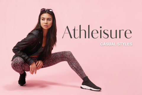 Eine hockende Person in einem stylischen Athleisure-Outfit, bestehend aus einer schwarzen Jacke, gemusterten Leggings und Sneakers. Der Hintergrund ist rosa mit dem Text „Athleisure Casual Styles“. Die Person trägt eine Sonnenbrille auf dem Kopf.