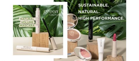 Eine Kollektion von Make-up-Produkten von Artdeco, darunter Mascara, Lippenstifte und Puder, präsentiert auf Holzklötzen mit großen grünen Blättern im Hintergrund. Der Text lautet: „Nachhaltig. Natürlich. Hohe Leistung. Mascara für natürliches Volumen. Green Couture.“.