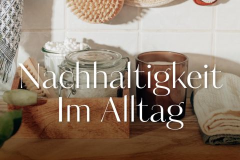 Eine gemütliche Küchentheke mit nachhaltigen Gegenständen: Vorratsglas, Spülbürste aus Holz und ein gefaltetes Handtuch. Auf dem deutschen Text steht „Nachhaltigkeit im Alltag“.