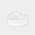 Weiße Keramikschale in Form eines Herzens, fotografiert auf einem schlichten hellgrauen Hintergrund.