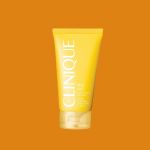 Eine gelbe Tube Clinique After Sun Rescue Balm mit Aloe steht auf einem orangefarbenen Hintergrund. Der Markenname ist in weißer Schrift deutlich zu erkennen.