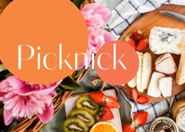 Ein Picknickplatz mit einem Holzbrett, auf dem verschiedene Käsesorten, Erdbeeren, Kiwischeiben und eine Orange liegen. Rosa Blumen rahmen die Szene ein und das Wort „Picknick“ steht in fetter Schrift auf einem orangefarbenen Kreis.