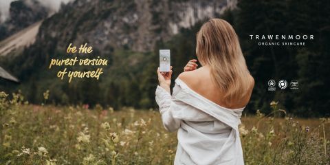 Eine Frau mit langen blonden Haaren steht mit abgewandtem Gesicht auf einem Feld und hält ein Hautpflegeprodukt in der Hand. Sie trägt ein schulterfreies Oberteil. Der Text lautet „Sei die reinste Version deiner selbst.“ Im Hintergrund sind Berge und Gras zu sehen. Auf dem Display ist „TRAWENMOOR ORGANIC SKINCARE“ zu sehen.