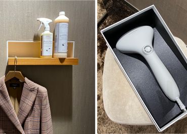 Links: Ein karierter Blazer auf einem Kleiderbügel unter einem Regal mit Textil-Sprühflaschen. Rechts: Ein Handdampfgerät in einer Schachtel auf einem beigen Stuhl.