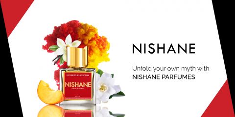 Eine Flasche Nishane-Parfüm mit goldenem Deckel ist von leuchtend roten, gelben und weißen Blumen umgeben. Daneben liegt eine Orangenschalenscheibe. Der Text lautet: „Enthüllen Sie Ihren eigenen Mythos mit NISHANE PARFUMES.“.