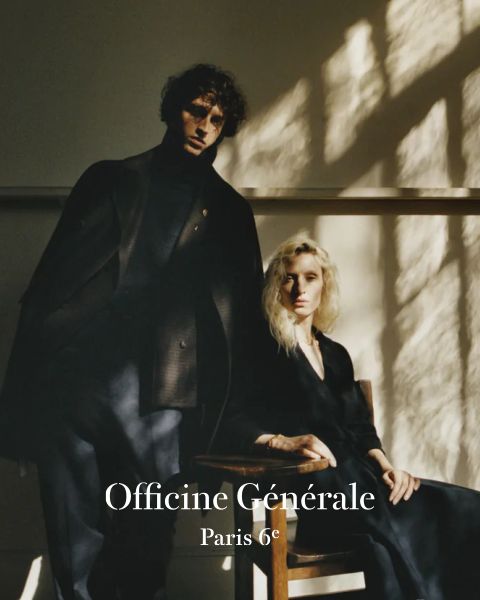 Ein Mann und eine Frau in dunkler, eleganter Kleidung posieren in einem sanft beleuchteten Raum mit Schatten aus einem Fenster. Der Mann steht und die Frau sitzt auf einem Holzstuhl. Der Text lautet „Officine Générale Paris 6e.