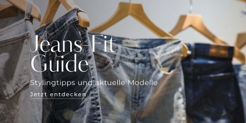 Auf Holzbügeln hängt eine Reihe Jeans in verschiedenen Farbtönen. Der Text lautet „Jeans-Fit Guide: Stylingtipps und aktuelle Modelle. Jetzt entdecken“ und deutet damit auf einen Ratgeber zu Styling und aktuellen Modellen hin.