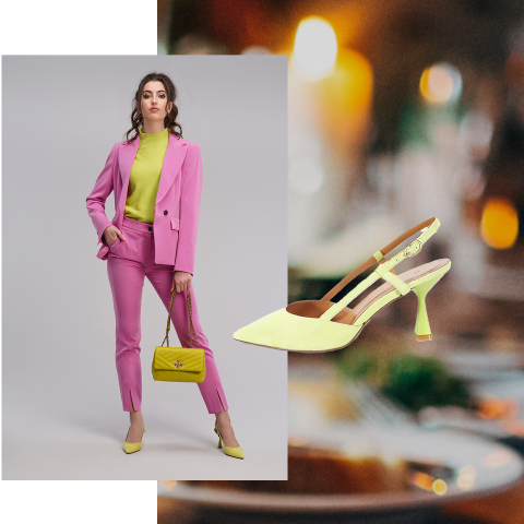 Eine Frau in einem leuchtend rosa Hosenanzug mit limettengrünem Oberteil und dazu passenden High Heels und Tasche steht vor einem grauen Hintergrund. Neben ihr ist eine Nahaufnahme eines limettengrünen High Heels vor einem unscharfen Hintergrund zu sehen.