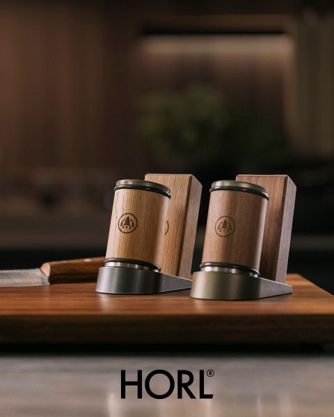 Zwei Messerschärfer aus Holz und Metall sowie ein Messerhalter aus Holz auf einer Holzunterlage, unten mit dem Logo „HORL“.