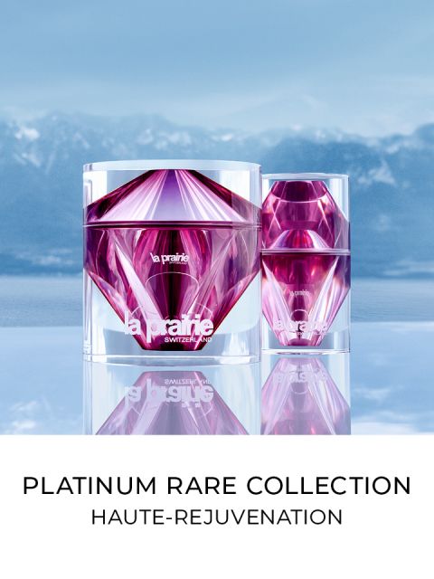 Zwei luxuriöse, facettierte Gefäße in rosa und violettem Farbton stehen vor einem Hintergrund aus blauem Himmel und Bergen. Unter den Gefäßen steht der Text „Platinum Rare Collection Haute-Rejuvenation“.